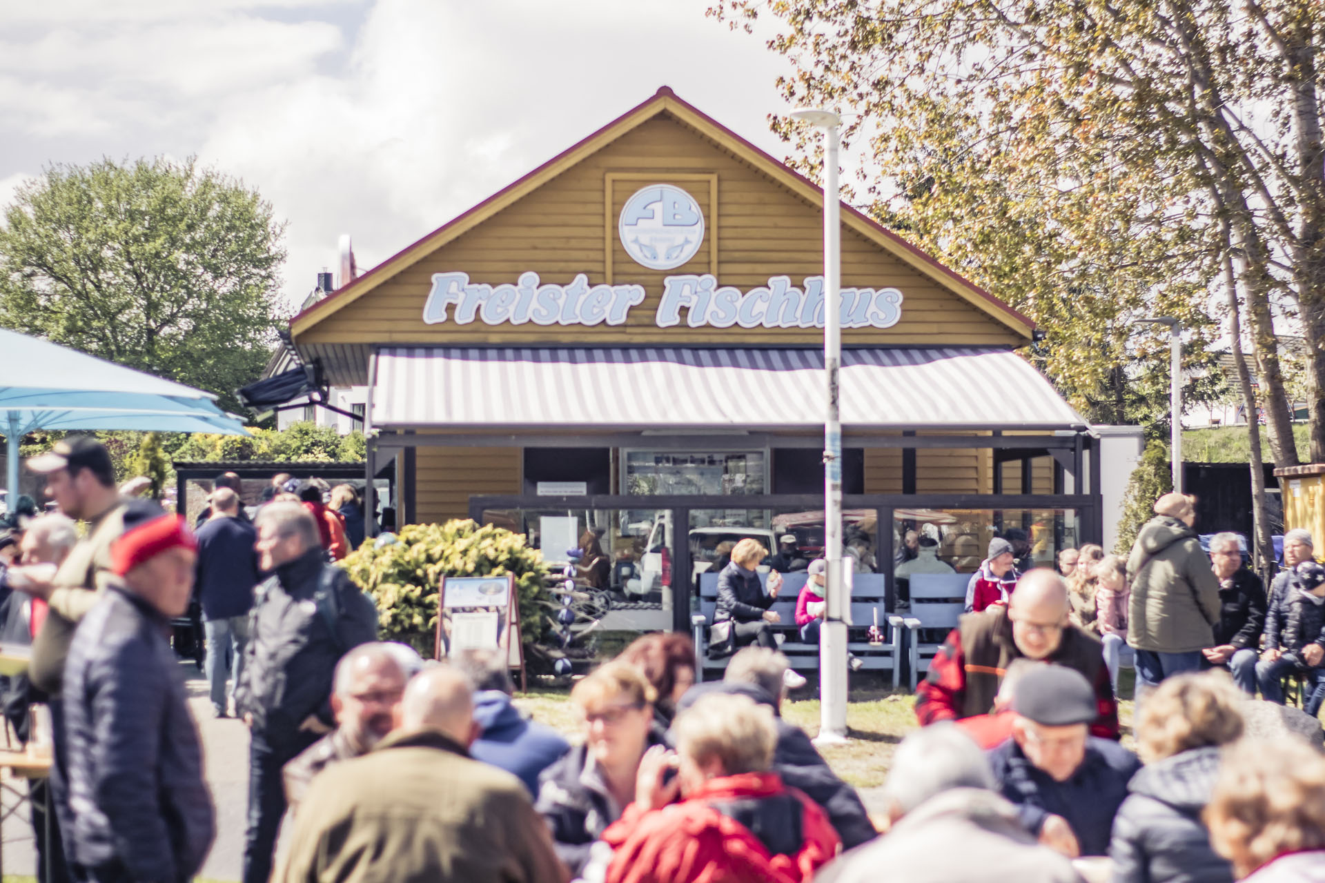 Blick auf das Freister Fischhus mit Menschen, die davor sitzen